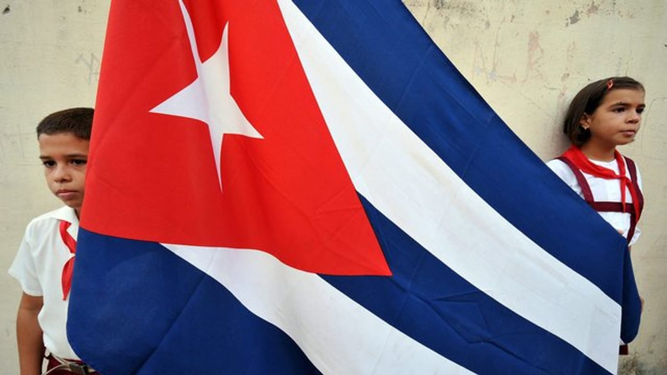 Ein kubanisches Schulkind neben der Fahne des Landes.