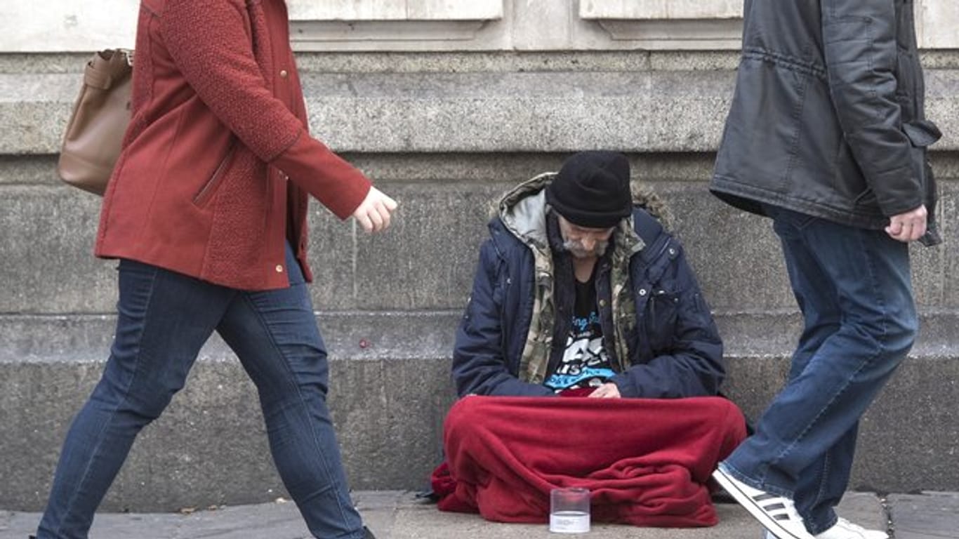 Ein Obdachloser sitzt vor der Victoria Station in London.