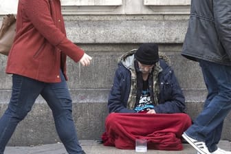 Ein Obdachloser sitzt vor der Victoria Station in London.