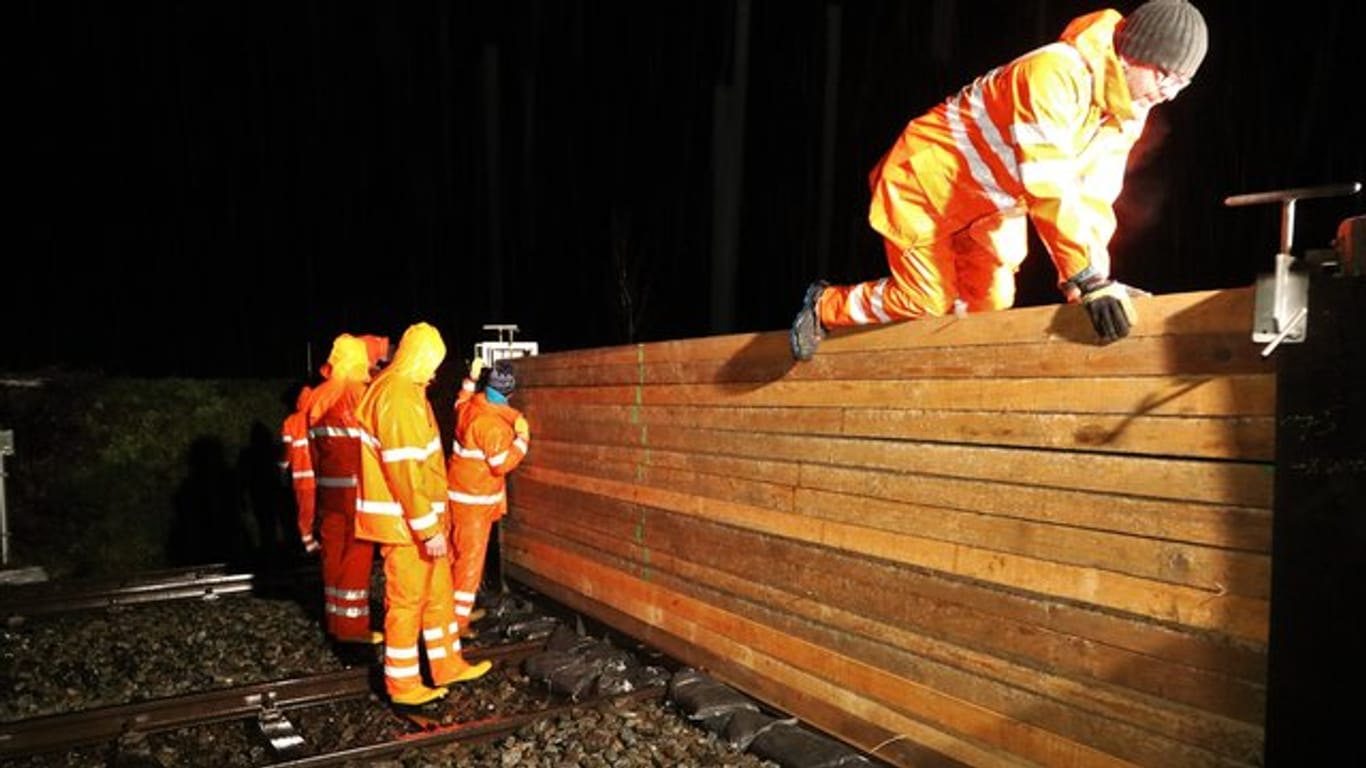 Mitarbeiter der Stadt Immenstadt bauen einen Schutzwall über eine Bahnstrecke.