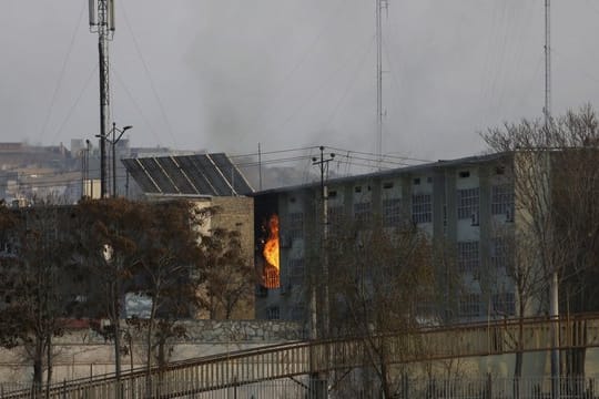 Aus einem Regierungsgebäude steigen nach einer Explosion Flammen auf.
