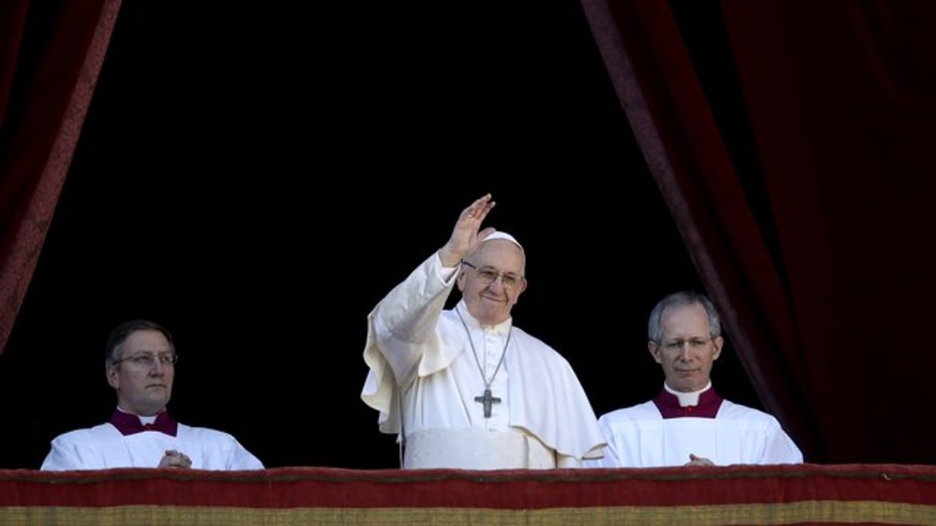 Papst Franziskus (M) winkt vom Hauptbalkon der Peterskirche im Vatikan.