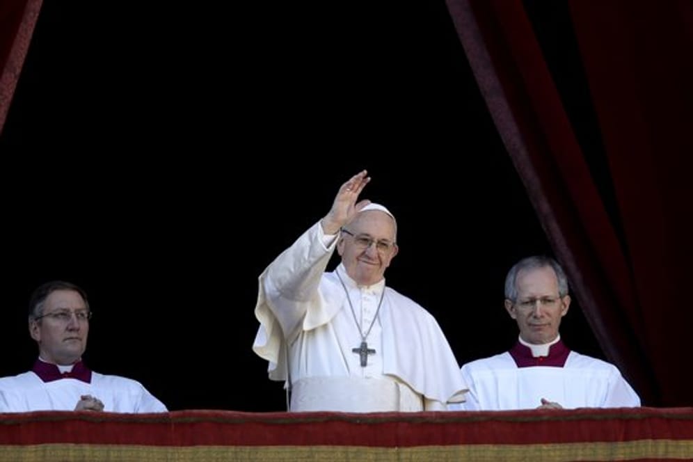 Papst Franziskus (M) winkt vom Hauptbalkon der Peterskirche im Vatikan.