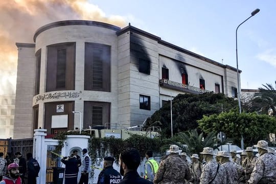Sanitäter und Sicherheitsleute vor dem Hauptquartier des Außenministeriums, über dem dichter Rauch zu sehen ist.