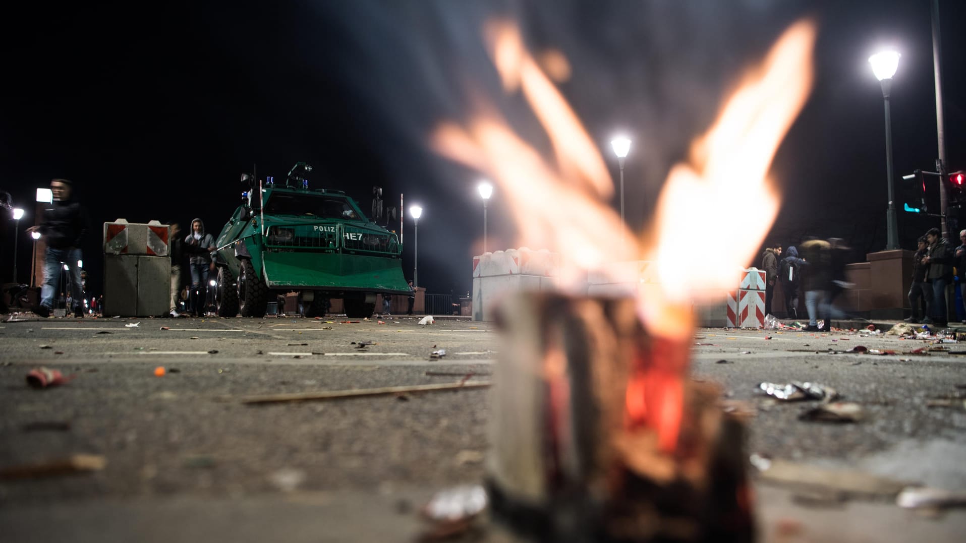 Ein ausgebrannter Feuerwerkskörper brennt in unmittelbarer Nähe eines gepanzerten Polizeifahrzeugs: Die Polizei bereitet sich schon auf Einsätze an Silvester vor.