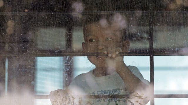 Ein Einwandererkind sieht aus der vergitterten scheibe eines Busses der US-Border Border Patrol. Ein Einwandererkind sieht aus der vergitterten scheibe eines Busses der US-Border Border Patrol.