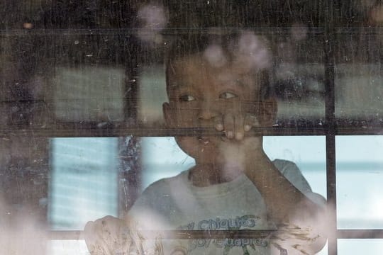Ein Einwandererkind sieht aus der vergitterten scheibe eines Busses der US-Border Border Patrol.
