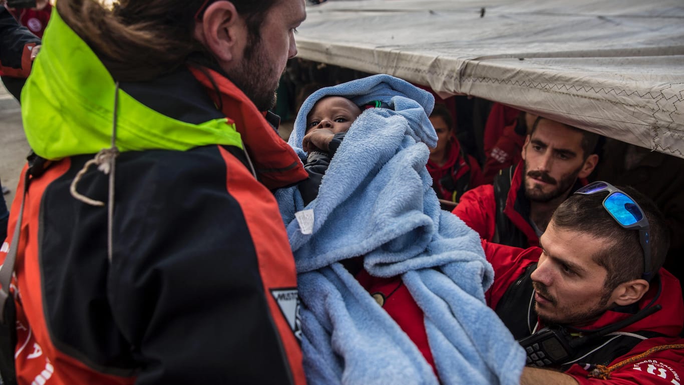 Helfer bringen ein Baby an Land: Das Rettungsschif mit Hunderten Flüchtlingen war eine Woche im Mittelmeer unterwegs.