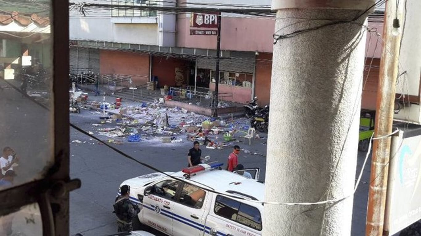 Polizisten untersuchen das Gelände vor einem Einkaufszentrum nach der Bombenexplosion.