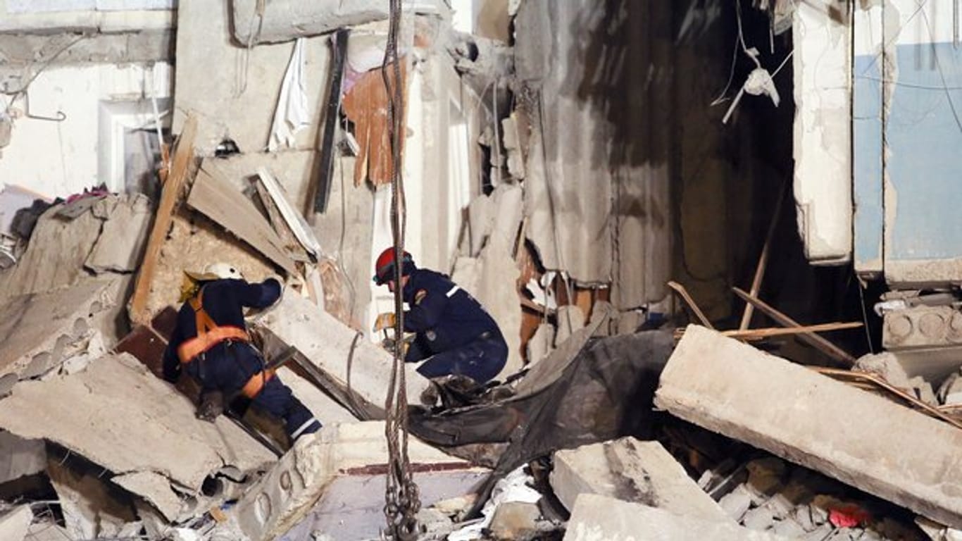 Rettungskräfte arbeiten in dem eingestürzten Mehrfamilienhaus.