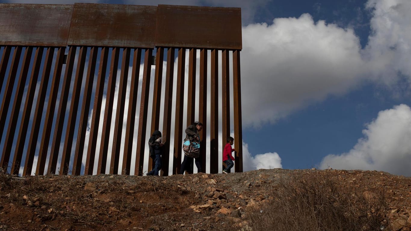 Migranten gehen vor einer Mauer bei Tijuana an der US-Grenze zu Mexiko entlang: Die Demokraten wollen US-Präsident Donald Trump kein Geld für seine komplette Grenzmauer geben.