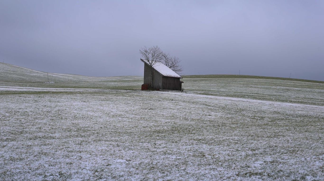 Ein Häuschen inmitten einer leicht mit Schnee bedeckten Allgäuer Landschaft: In mehreren Regionen Deutschlands soll es die nächsten Tage schneien.