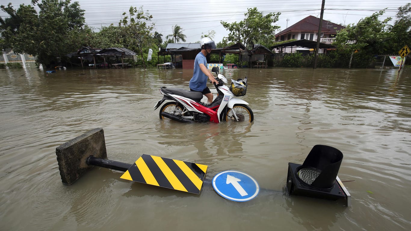 Mann schiebt Motorrad durch Wasser: Der Tropensturm Pabuk wütet auf Thailand.