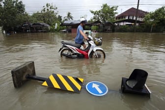 Mann schiebt Motorrad durch Wasser: Der Tropensturm Pabuk wütet auf Thailand.