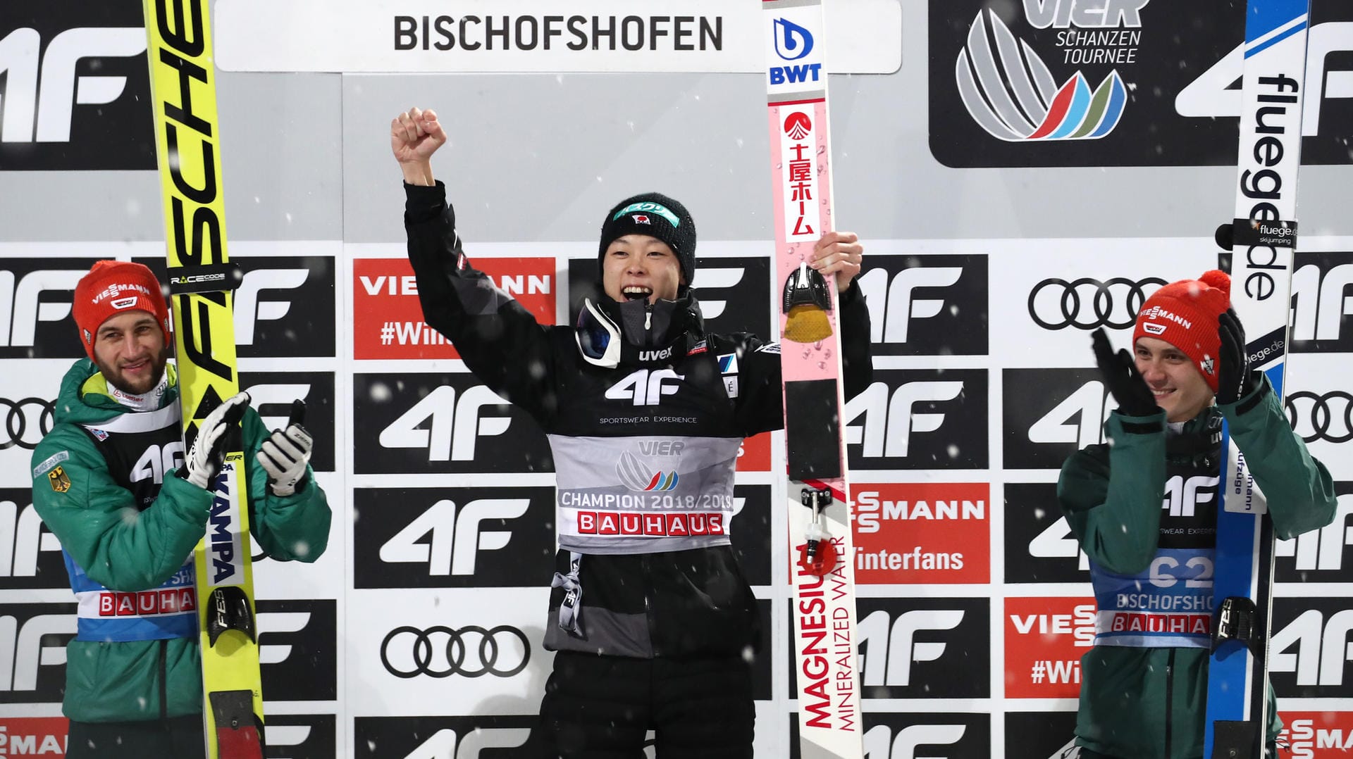 Markus Eisenbichler (links) und Stephan Leyhe (rechts) aus Deutschland applaudieren dem Gesamtsieger Ryoyu Kobayashi aus Japan.