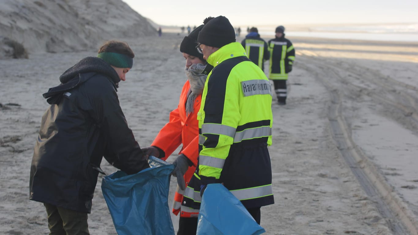 Einsatzkräfte und freiwillige Helfer sammeln auf Borkum: Wegen der Havarie wird immer mehr Treibgut angespült.
