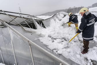 Salzburg in Österreich: Feuerwehrmänner schippen Schnee von einem eingebrochenen Gewächshausdach.