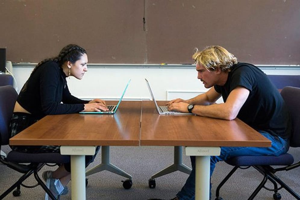 Zwei Studenten der San Francisco State University zeigen, wie Menschen ihren Hals am Computer zusammendrücken.