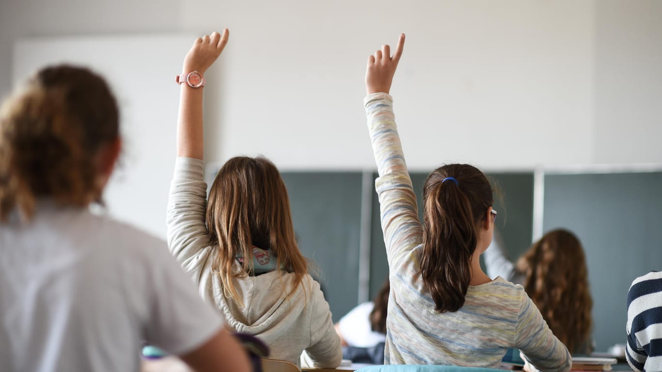 Zwei Schülerinnen heben im Unterricht die Hand (Symbolbild): Datenschutz muss an Schulen bundesweit Thema werden.