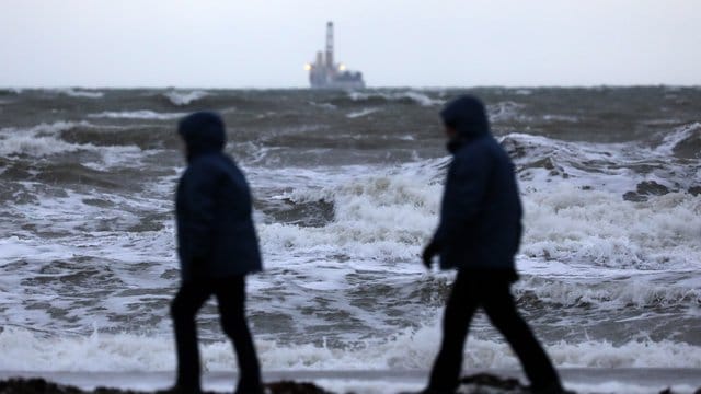 Spaziergänger sind in Warnemünde an der aufgewühlten Ostsee unterwegs. Spaziergänger sind in Warnemünde an der aufgewühlten Ostsee unterwegs.