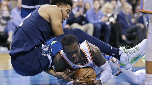 OKC-Spieler Dennis Schröder (r) kommt bei einer Attacke von Minnesotas Karl-Anthony Towns zu Fall. OKC-Spieler Dennis Schröder (r) kommt bei einer Attacke von Minnesotas Karl-Anthony Towns zu Fall.