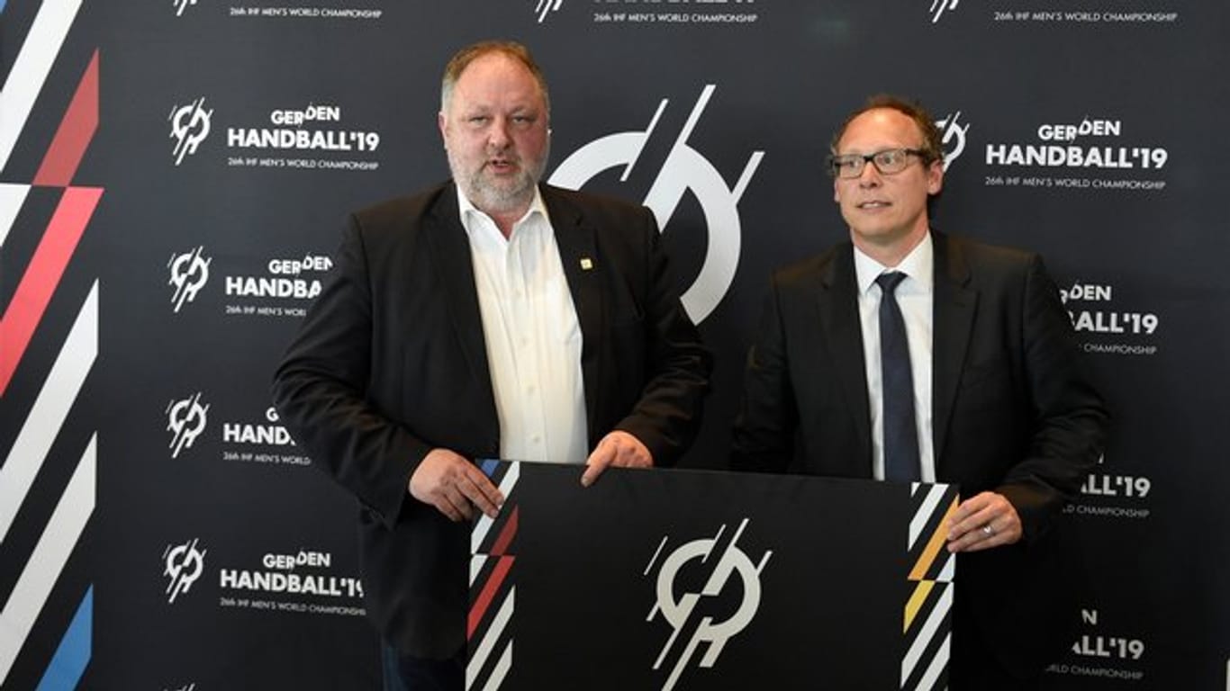 DHB-Präsident Andreas Michelmann (l) und der DHB-Generalsekretär Mark Schober posieren mit einem WM-Plakata.