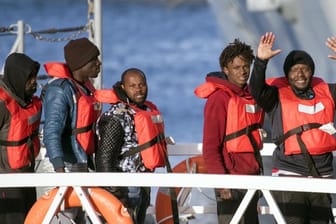 Migranten winken, als sie eins der deutschen Rettungsschiffe im Hafen von Pieta auf Malta verlassen dürfen.