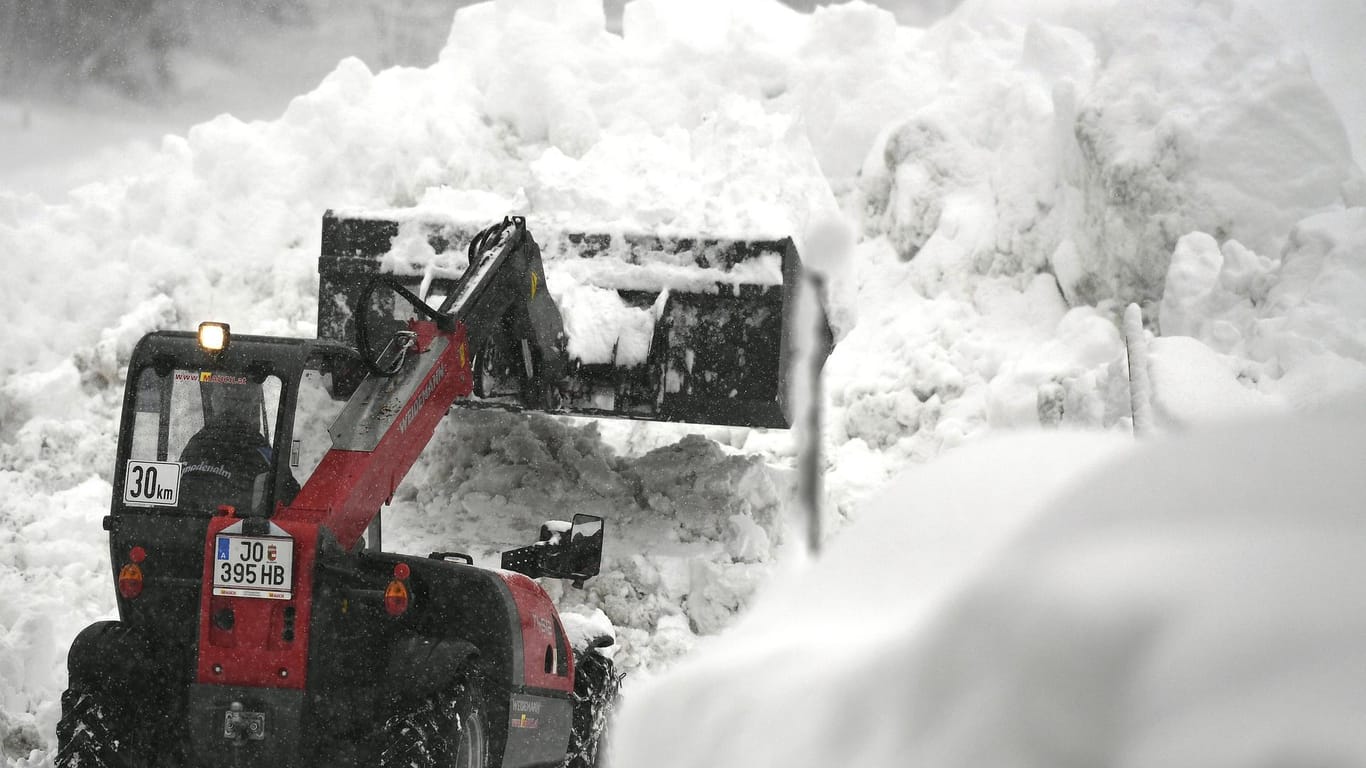 Ein Bagger räumt Schneemassen in den Alpen: Bis Freitag soll es non-stop schneien, am Samstag gibt es eine kurze Verschnaufpause – und dann geht es wieder los. Bis Mitte nächster Woche ist keine Entspannung in Sicht.