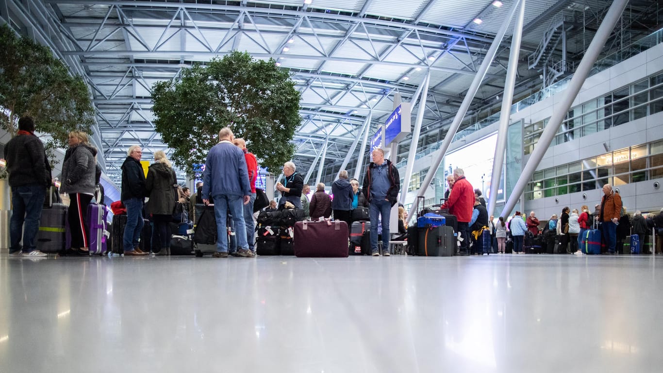 Menschen warten mit ihrem Gepäck am Flughafen Düsseldorf: Von den Warnstreiks sind rund 111.000 Reisende betroffen.