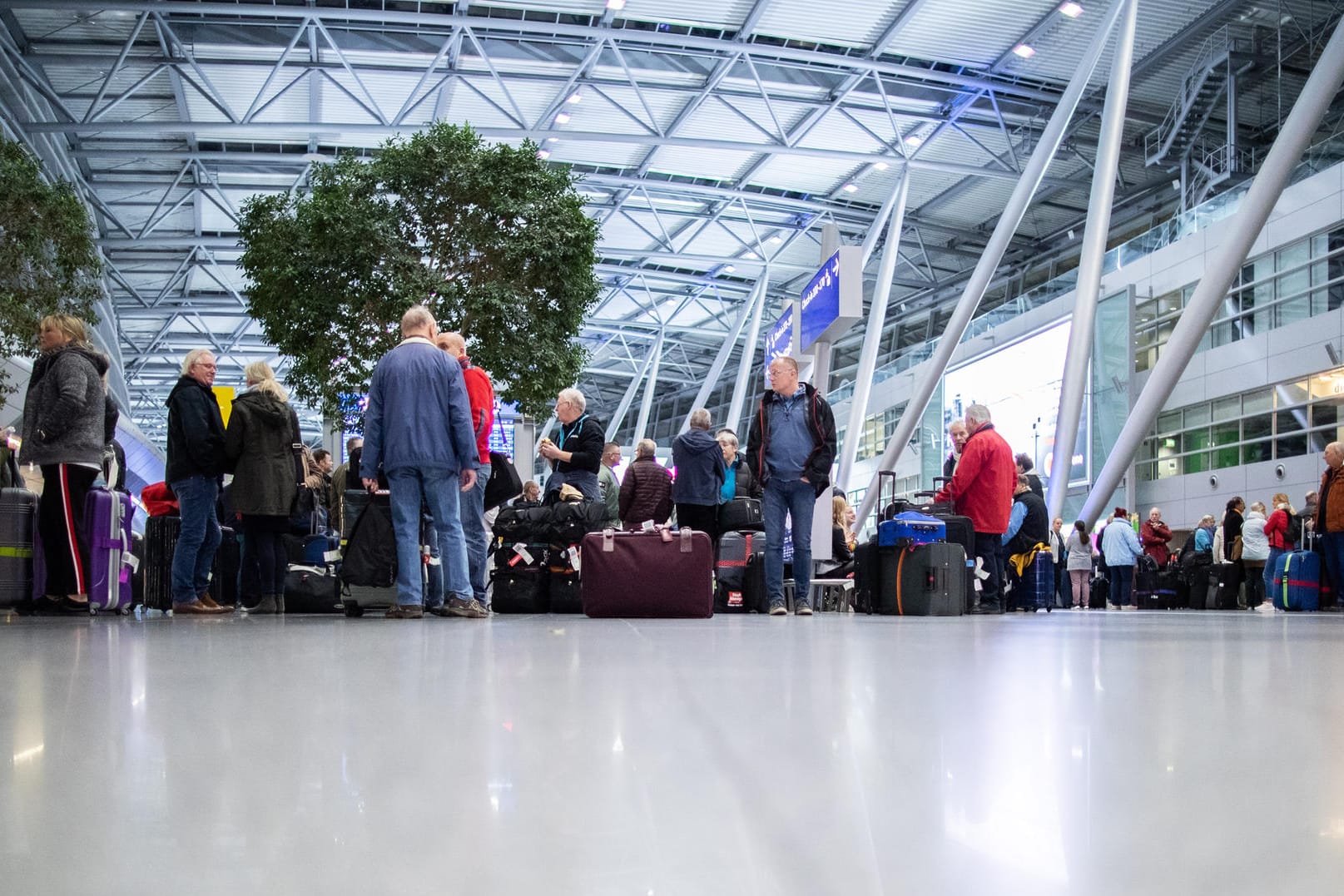 Menschen warten mit ihrem Gepäck am Flughafen Düsseldorf: Von den Warnstreiks sind rund 111.000 Reisende betroffen.