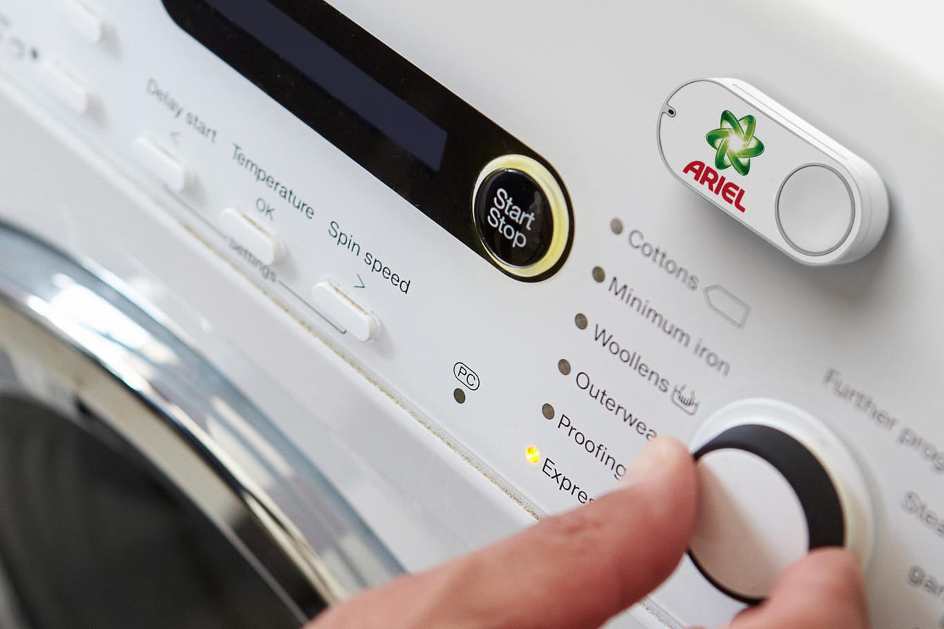 Das Foto zeigt einen Amazon Dash Button für die Marke Ariel, der an einer Waschmaschine klebt: Per Knopfdruck lässt sich beispielsweise neues Waschmittel bestellt.