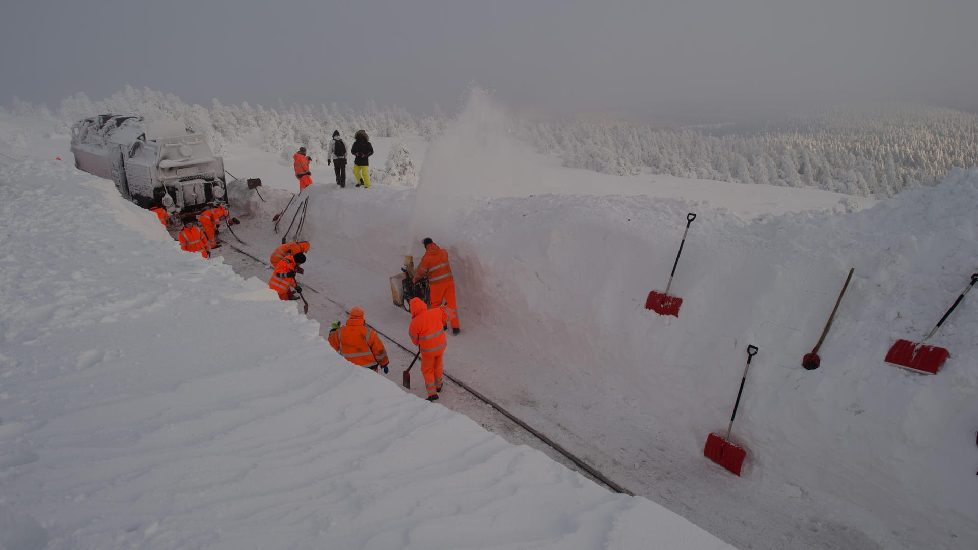 Arbeiter befreien auf dem Brocken, wenige hundert Meter vom Brockenbahnhof entfernt, eine Lokomotive der Brockenbahn aus dem Schnee.