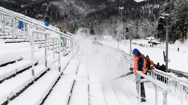 Helfer befreien die Zuschauertribünen in Ruhpolding vom Schnee.
