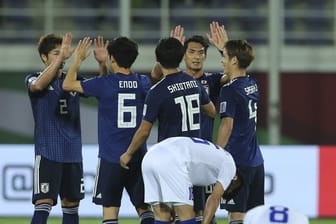 Japans Spieler (hinten) feiern den Sieg über Usbekistan.