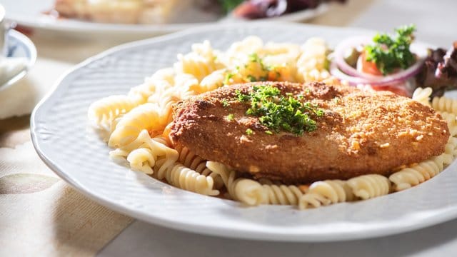 Das Jägerschnitzel ist eine panierte Jagdwurstscheibe, meist serviert mit Spirelli und einer Tomatensauce.