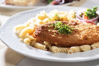 Das Jägerschnitzel ist eine panierte Jagdwurstscheibe, meist serviert mit Spirelli und einer Tomatensauce.