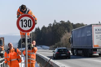 Straßenwärter montieren ein neues Tempo-130-Schild: Für mehr Klimaschutz im Verkehr spricht eine Regierungskommission auch über Tempolimits auf Autobahnen.