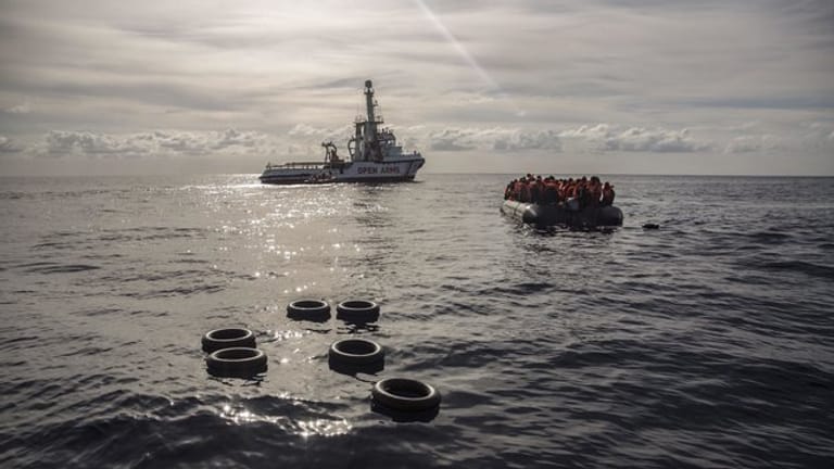 Migranten sitzen in einem Schlauchboot, nachdem sie im Mittelmeer entdeckt und gerettet wurden.