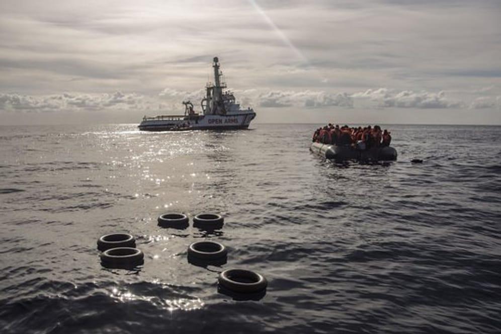 Migranten sitzen in einem Schlauchboot, nachdem sie im Mittelmeer entdeckt und gerettet wurden.