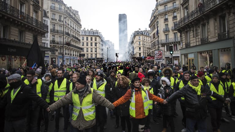 Teilnehmer der "Gelbwesten"-Proteste halten sich an den Händen: In ganz Frankreich nahmen 84.000 Menschen an den Protesten teil.