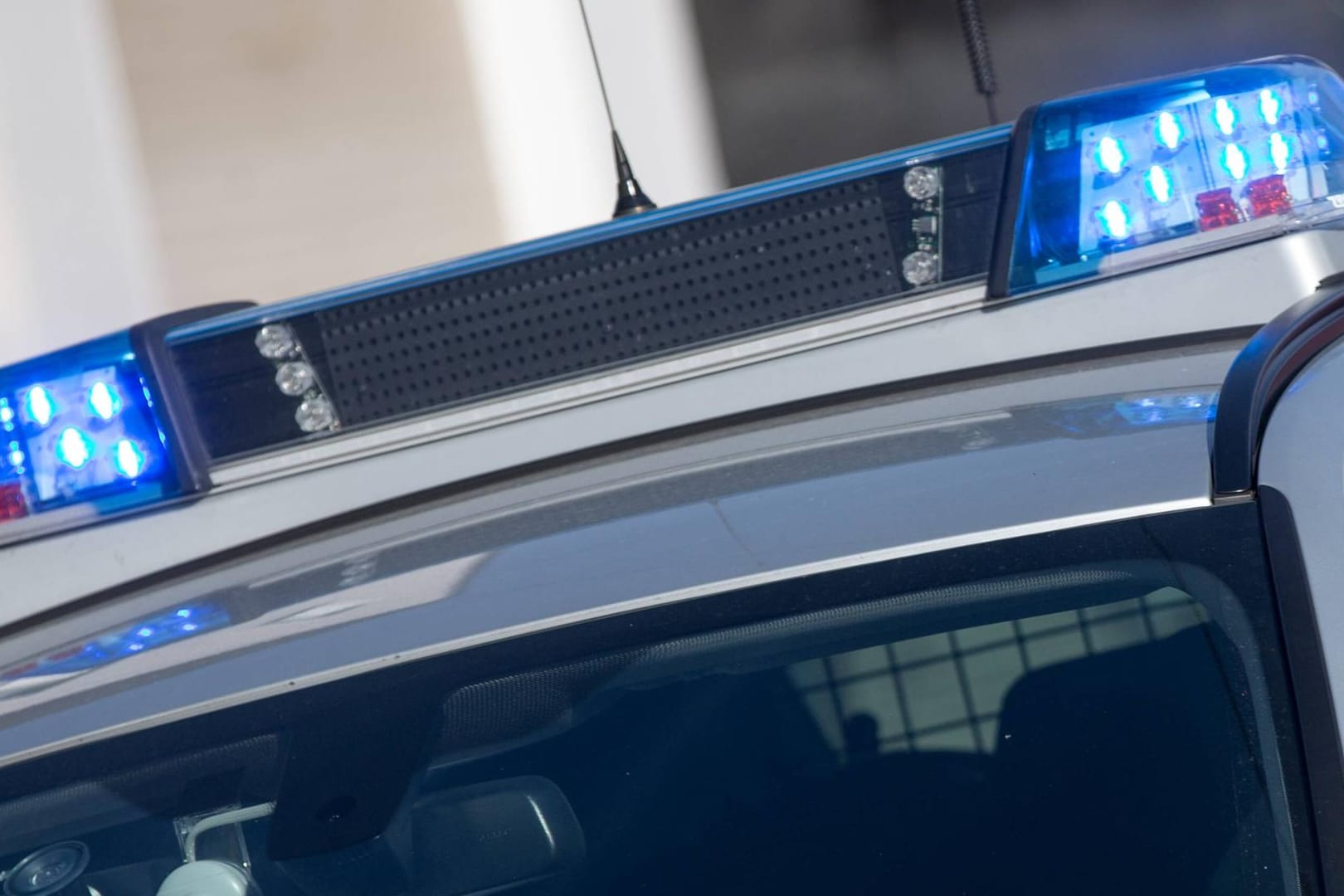 Blinkendes Blaulicht auf dem Dach eines Einsatzfahrzeuges der Polizei: In Hessen wird nach einer bewaffneten Frau gefahndet.