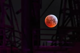 Als roter, sogenannter "Blutmond" präsentiert sich der Vollmond zwischen einer Industrieanlage im Landschaftspark Duisburg, während er in den Kernschatten der von der Sonnen angestrahlte Erde tritt. Der Kernschatten verdeckt dabei die sichtbare Oberfläche des Mondes. Mond, Sonne und Erde stehen genau in einer Linie.