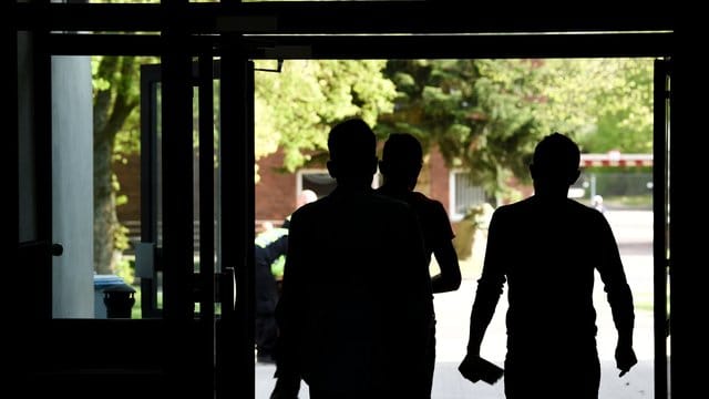 Drei Asylbewerber laufen aus einem Gebäude der Landeserstaufnahmeeinrichtung hinaus. Drei Asylbewerber laufen aus einem Gebäude der Landeserstaufnahmeeinrichtung hinaus.