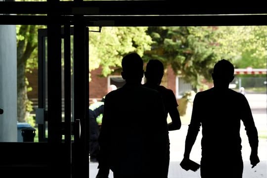 Drei Asylbewerber laufen aus einem Gebäude der Landeserstaufnahmeeinrichtung hinaus.