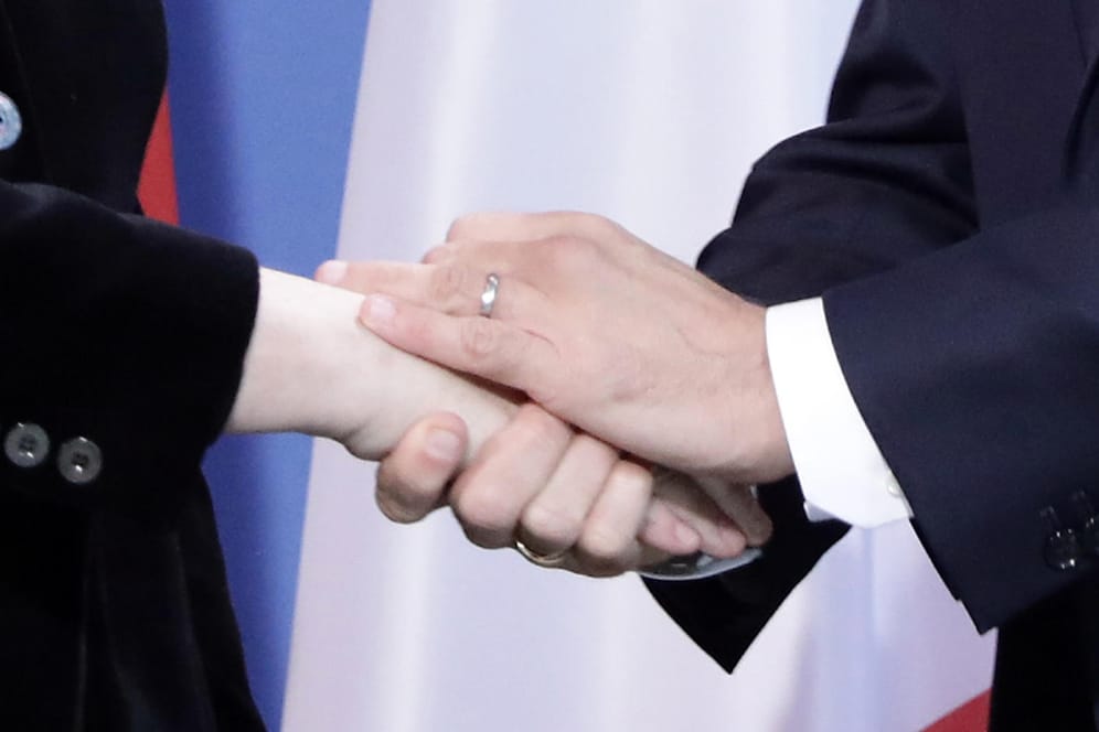 Merkel und Macron reichen sich die Hände.