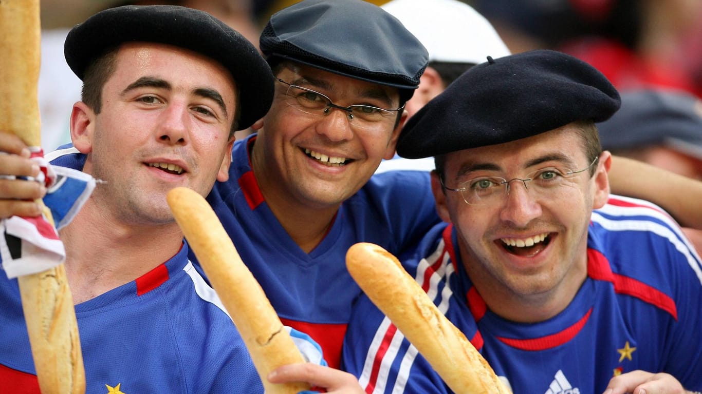 Drei frische Franzosen mit Baguette und Baskenmütze bestätigen das Klischee: Diese Bild wurde 2006 bei einem Fußballspiel aufgenommen. Auch im Fußball können Franzosen den Deutschen aktuell was beibringen.