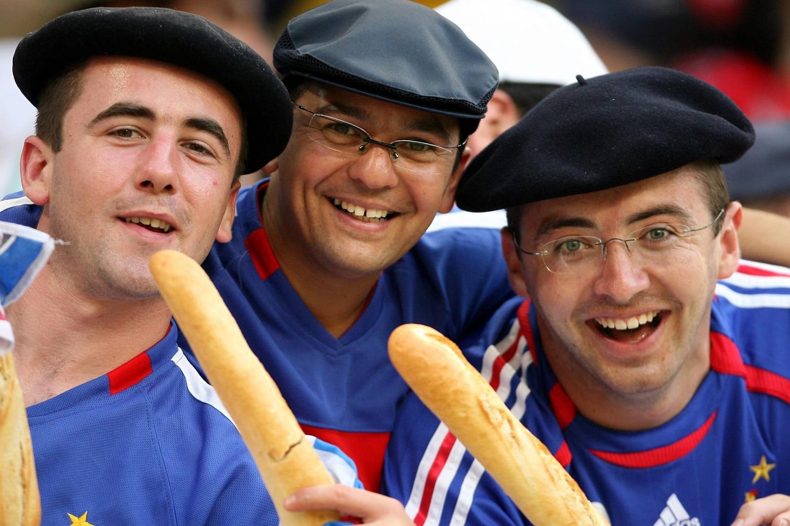 Drei frische Franzosen mit Baguette und Baskenmütze bestätigen das Klischee: Diese Bild wurde 2006 bei einem Fußballspiel aufgenommen. Auch im Fußball können Franzosen den Deutschen aktuell was beibringen.