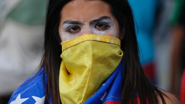 Demonstrantin in Caracas: Ihr Gesicht hat die junge Frau mit der venezolanischen Flagge umwickelt, um die Augen hat sie Zahnpasta geschmiert, um die Wirkung des Tränengases zu mindern.