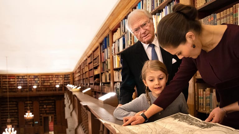Drei Generationen: König Carl Gustaf, Prinzessin Estelle und Kronprinzessin Victoria besuchen die Bernadatto-Bibliothek.