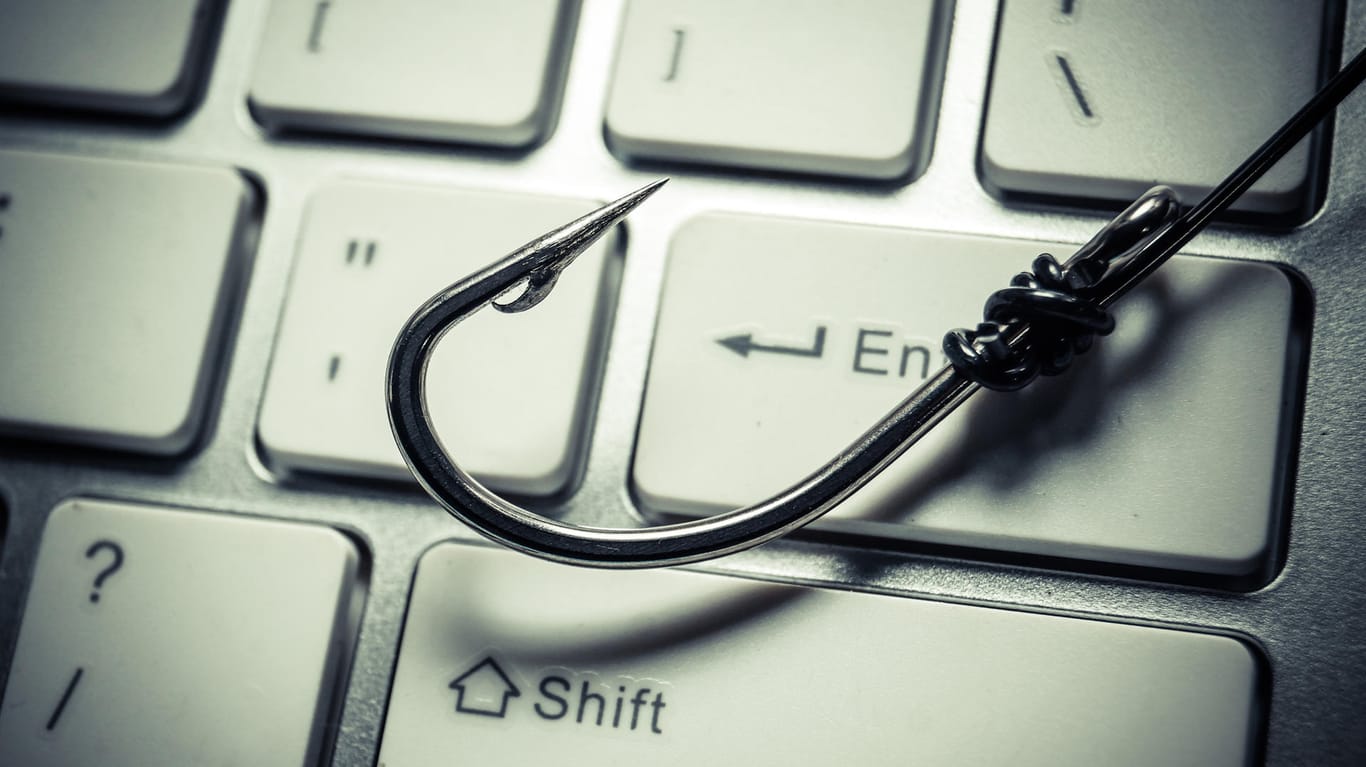 Ein Angelhaken auf einer Tastatur (Symbolbild): Mithilfe von Phishing-Mails versuchen Kriminelle an Daten von Nutzern zu kommen.